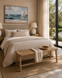 Mediterranean bedroom with natural wood bedside tables, woven bench, soft linen textiles and coastal artwork in a calm Mallorca-