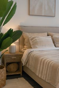 Handcrafted Swedish boxspring bed with striped bedding, upholstered headboard and soft natural textiles in a relaxed Mediterrane
