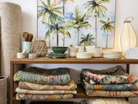 Mediterranean home decoration with colourful vintage kilim rugs, ceramic tableware, woven textures and tropical artwork in a rel