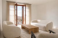 Modern lounge area in a Santa Catalina townhouse in Palma with curved bouclé sofas, rustic wooden coffee table, soft neutral ton