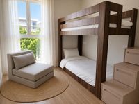 Dormitorio infantil contempor&aacute;neo en Es Molinar con litera de madera oscura, luz natural y mobiliario funcional en apartamento mediterr&aacute;neo de Palma de Mallorca.