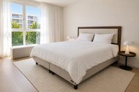 Cama continental sueca con cabecero en nogal y bouclé en dormitorio contemporáneo de Es Molinar con luz natural y estilo mediterráneo relajado en Palma de Mallorca.
