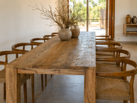 Rustic wooden dining table with woven chairs in a relaxed countryside home in Porreres, Mallorca, featuring natural materials and warm Mediterranean interior styling.