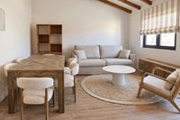 Living and dining area of a Santa Catalina penthouse with natural wood furniture, neutral tones and soft Mediterranean styling.