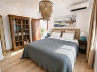 Bright Mediterranean bedroom in Palma Old Town with upholstered bed, natural oak flooring, warm wood furniture and relaxed coastal styling on Mallorca.