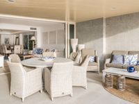 Covered Mediterranean terrace in Portixol with outdoor dining area, lounge seating and open connection to the interior living space in Palma de Mallorca.