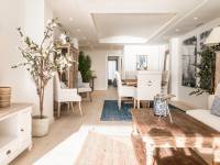 Open-plan Hamptons-style Mediterranean living and dining room in Portixol with rustic wood furniture, blue accents and relaxed coastal atmosphere in Palma de Mallorca.